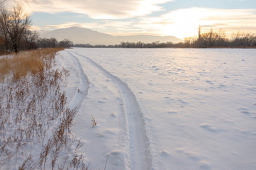 Fototapeta na wymiar Tire track in the snow to the horizon