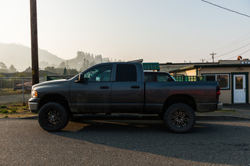 Large dark gray 4x4 pickup at sunrise in Gold Beach