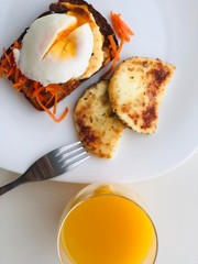 Breakfast sandwich with grilled cheese, poached egg and carrots on white background