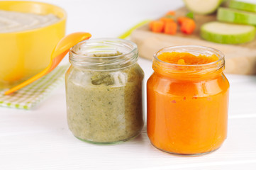 Broccoli and pumpkin puree in jars on white wooden background