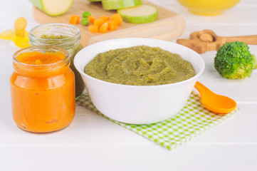 Vegetable puree in the plate and jar on wooden background