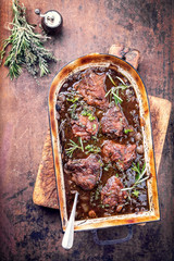 Traditionelle geschmorte Kalbsbäckchen in brauner Rotwein Sauce mit Pilzen und Zwiebel als...