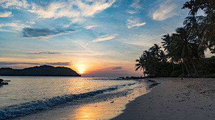 Beautiful charming sunset by the sae on the beach of Phu Quoc island with beautiful view of palms,mountains and orange sky