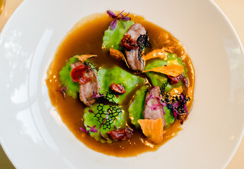 ravioli green in meat broth with pieces of seafood and dried tomatoes