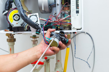 worker set up central gas heating boiler at home