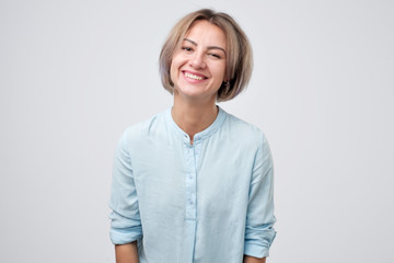 Friendly happy female coworker with beautiful face and smile, gazing at camera with positive joyful attitude at studio