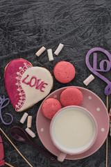 Romantic Valentine's Day breakfast. Heart-shaped cookies and a cup of milk on a gray table. Top view