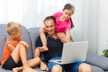 Smiing parent and focused daughter using laptop at home