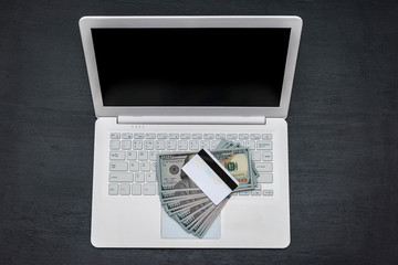 White laptop with dollars and credit card isolated