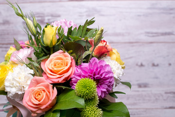 beautiful floral arrangement in the box, pink and yellow rose, pink eustoma, green and pink chrysanthemum, white carnation, dahlia on wooden background, top view, with space for text