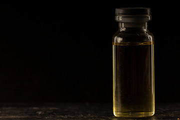 small medical Bottle, with yellow inside, on a black background, close-up,
