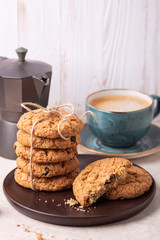 Cup of coffee, stack of oatmeal cookies, coffee maker on white wooden background Homemade bakery Healthy food snack concept