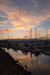 Colorful pink sunset reflecting over sailboats in the harbor at San Diego California