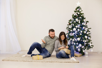 Obraz premium man and woman open Christmas gifts at the Christmas tree new year