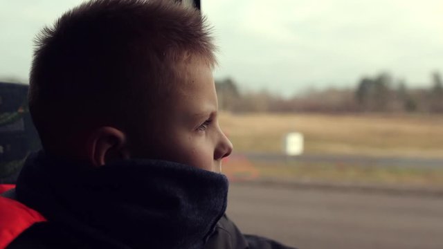 One little kid boy sit in car and look at window, unhappy face. Unhappy children in winter clothes sitting in car. - Image