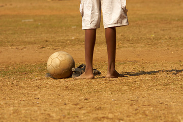 Young captain of a football team standing barefoot in the goal after letting a ball in on the dusty cricket field in Mumbai, India
