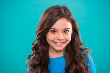 Perfect curling hair. Kid girl long healthy shiny hair. Kid happy cute face with adorable curly...