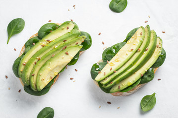 Two ciabatta toast with sliced avocado olive oil, spinach and flax and sesame seeds. Healthy...
