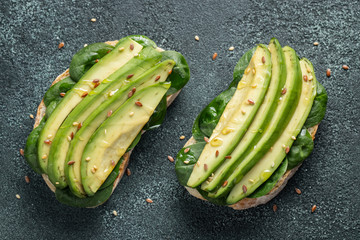 Two ciabatta toast with sliced avocado olive oil, spinach and flax and sesame seeds. Healthy...