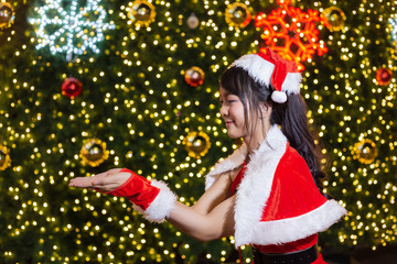Happy smiling Santa girl is cute in red suit with christmas tree background celebration in christmas and happy new year festival.