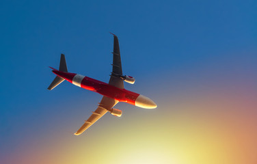 Airplane in the sky from underneath with sun rays in morning day.