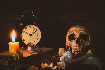 Still life with human skull vintage antique Bell Clock, candle, glass and grunge book