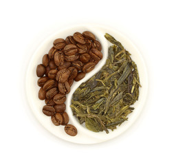 Roasted coffee beans and green tea in round Yin and Yang saucer on white background