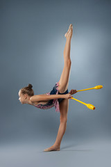 Beautiful gymnast girl in sportswear, rhythmic gymnastics element with mace on gray background