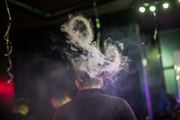 Fototapeta na wymiar Circle of smoke from electronic cigarettes. Couples from vape. Smoke from the mouth of a smoking man. Men vaping and lets out circles of smoke.