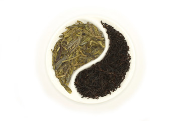 Green and black tea in round Yin and Yang saucer on white background