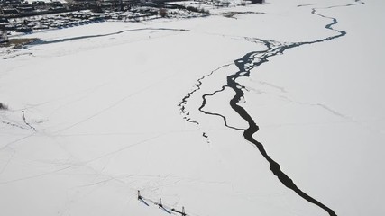 Aerial drone shot of icy, snow covered lake with pier and cracks in the ice - BC Canada