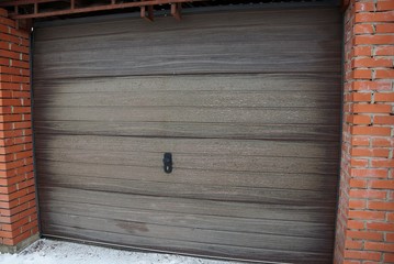 brown closed gate on the facade of a garage outside in the snow
