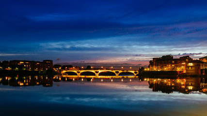 Fototapeta na wymiar Garonne River at dusk with reflections of bridge and buildings, in Toulouse, France