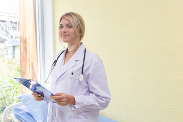 Woman doctor standing holding folder in Patient Room at hospital