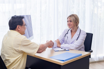 Woman doctor and male patient discussing handshake After the conclusion, the treatment at the desk at hospital.