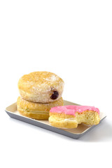 Strawberry donut is bitten put with couple donuts on plate isolated on white background.
