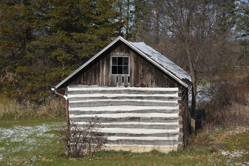 Old log cabin storage building on the edge of a forest in winter