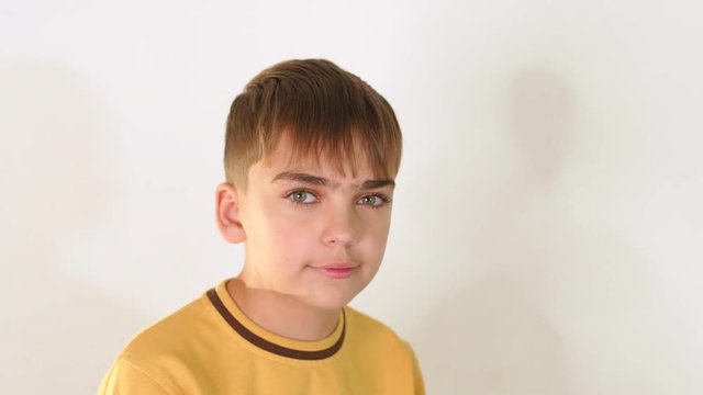 Portrait of a cute young black-haired boy on a white background in the Studio, he is wearing a yellow jacket. Slow motion.