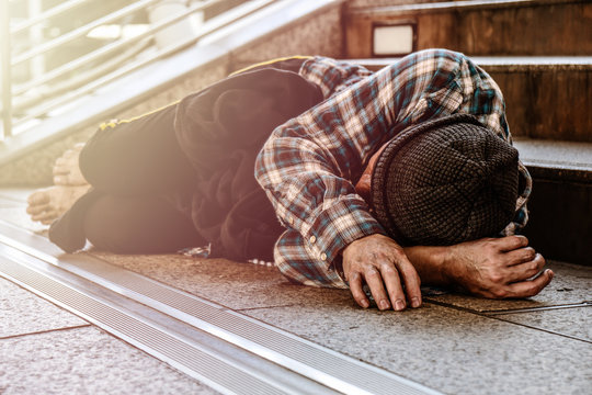 Asian male poor homeless man sleeping on pathway with suffering and sad