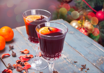 Two wineglass with Christmas mulled red wine with spices and fruits on a wooden rustic table.