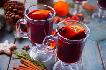 Two wineglass with Christmas mulled red wine with spices and fruits on a wooden rustic table.