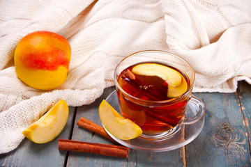 Drink of apple tea with cinnamon stick, star anise and clove. Seasonal punch in cup on wooden background.
