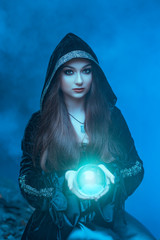 The witch with magic ball in her hands causes a spirits