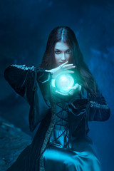 The witch with magic ball in her hands causes a spirits - obrazy, fototapety, plakaty