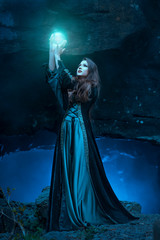 The witch with magic ball in her hands causes a spirits - obrazy, fototapety, plakaty