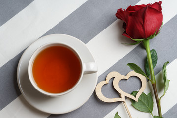 Romantic still life with a cup of tea and bright red holiday attributes.