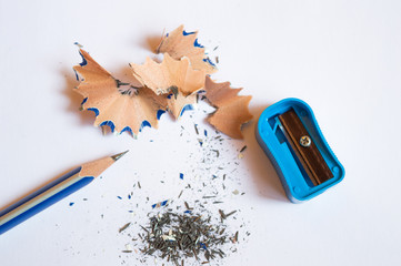 A pencil sharpened with a sharpener with pencil peels and black graphite lead waste on a white background