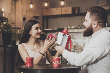 Bearded man gives a present to beautiful girl