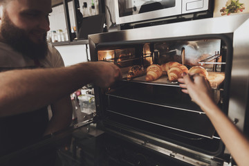 Two professional bakers are standing near oven.