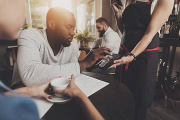 Young afro american is paying in a contactless way